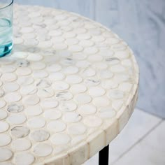 a glass sitting on top of a marble table next to a vase filled with water