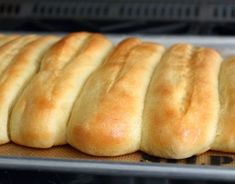 freshly baked bread rolls lined up on a baking sheet in the oven, ready to go into the oven