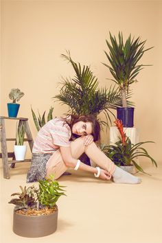 a woman kneeling on the ground in front of potted plants with text overlay reading strange botany