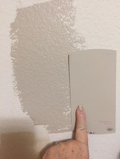 a hand pointing at a white paint on the wall