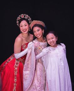 three women in dresses and tiaras posing for a photo with one woman holding the other