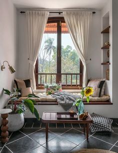 a living room filled with furniture next to a window covered in white curtains and sunflowers