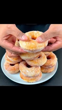 two hands holding donuts stacked on top of each other