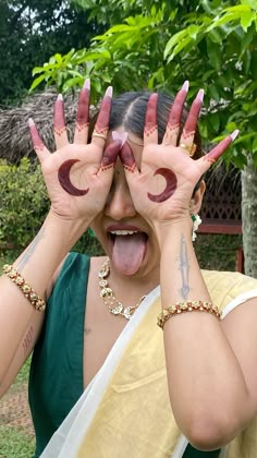 a woman with her hands in the air and painted on to her face, making faces