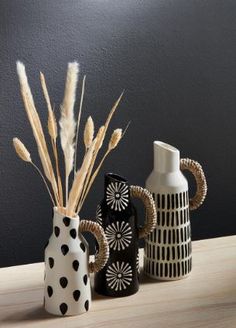 three ceramic vases sitting on top of a wooden table next to each other,