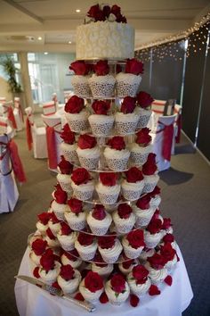 a wedding cake made out of cupcakes with red roses on the bottom tier