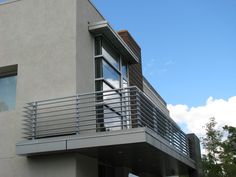 an apartment building with a metal balcony and balconies on the upper level overlooking trees