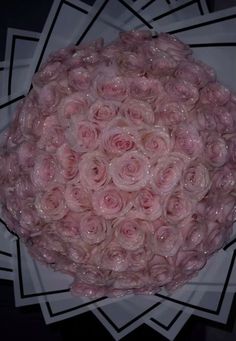 a bouquet of pink roses sitting on top of a white paper plate in front of a black background