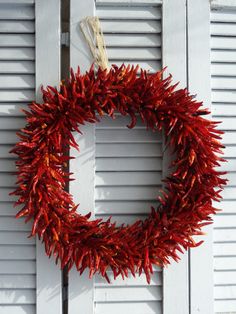 a close up of a wreath on a door with shutters in the back ground