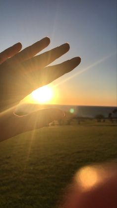 the sun is setting behind someone's hand