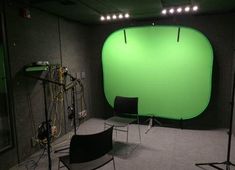 an empty room with green screen and chairs