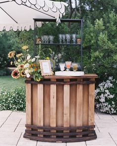 a wooden bar with flowers and drinks on it in the middle of a patio area