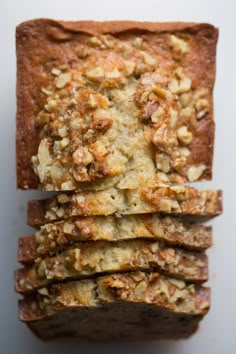 sliced bread with nuts on top sitting on a white surface