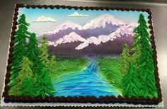 a cake decorated with trees and mountains on top of a metal surface, in the shape of a river