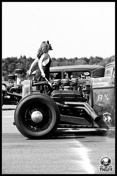 a woman standing on top of an old fashioned car in the middle of a race