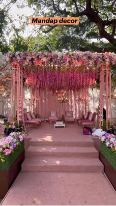 an outdoor wedding setup with pink flowers and greenery on the steps to the aisle