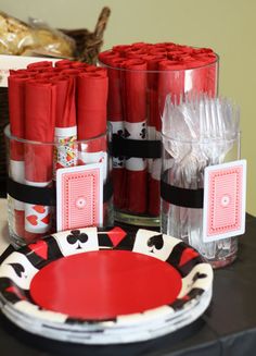 a table topped with lots of red and black napkins next to stacks of cards