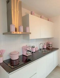 a kitchen with white cabinets and pink appliances on the counter top in front of it