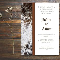 a wedding card with a cow print on it and a flower in the middle, sitting on top of a wooden table