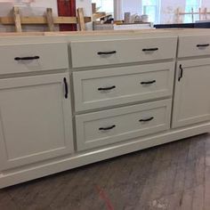 an unfinished kitchen with white cabinets and wood floors