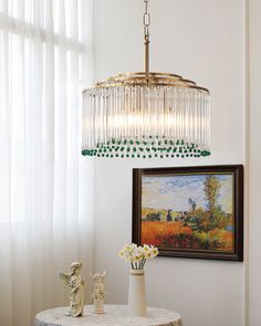 a chandelier hanging over a table in a room with paintings on the wall