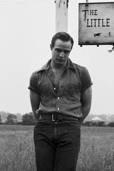 black and white photograph of a man standing in front of the little mohe sign