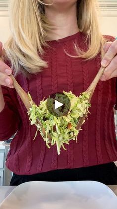 a woman holding a wooden spoon with some food on it