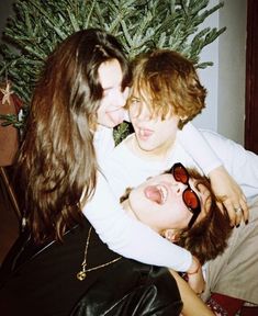 two young women hugging each other in front of a christmas tree with her eyes closed