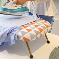 a woman ironing fabric on an ironing board with a blue and white iron