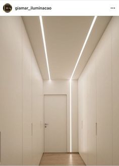 an empty hallway with white walls and wooden floors is lit by led lighting from the ceiling