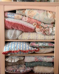 a shelf filled with lots of pillows and blankets