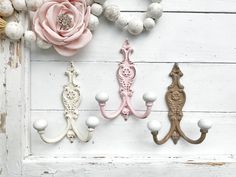 three decorative hooks are hanging on a white wood paneled wall with flowers and balls around them