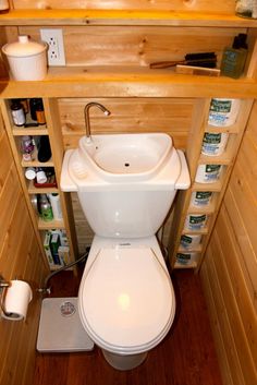 there is a small bathroom with wooden walls and shelves on the wall above the toilet