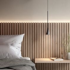 a bed sitting next to a wooden wall with a lamp hanging above it and a book on top of the bed