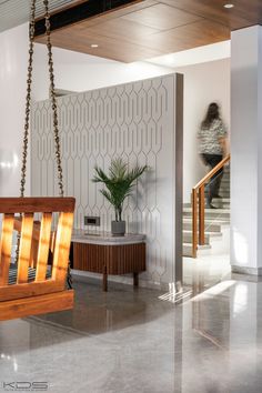 a wooden swing hanging from the ceiling in a room with white walls and wood accents