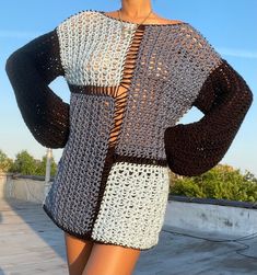 a woman wearing a crocheted sweater with her hands on her hips