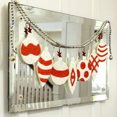 a mirror with ornaments hanging from it's sides in front of a white wall