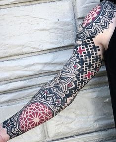 a man's arm with an intricate tattoo design on the forearm and hand, in front of a white brick wall