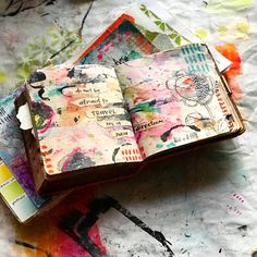 an open book sitting on top of a table covered in lots of different colored papers