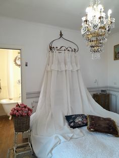 a bed with a white canopy and chandelier in a room filled with furniture