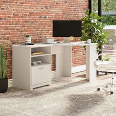 a computer desk with a monitor and keyboard on it in front of a brick wall