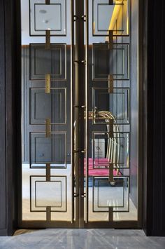 an open glass door leading into a room with a pink chair in the corner and yellow chairs