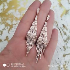 the pair of earrings is being held in someone's hand