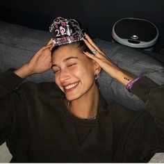 a woman wearing a tiara sitting on a couch with her hands to her head