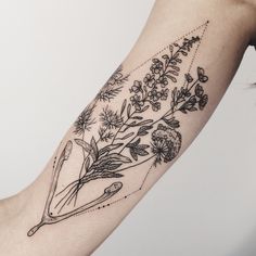 a woman's arm with flowers and scissors tattooed on the left side of her arm