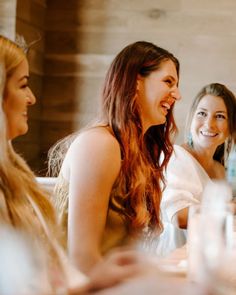 three women sitting at a table laughing together