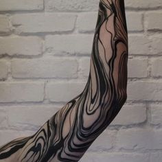 a person's arm with black and white ink on it in front of a brick wall