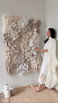 a woman standing in front of a large wall sculpture