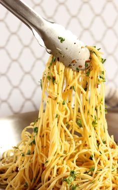 someone is holding a fork full of spaghetti with parmesan cheese and herbs on top