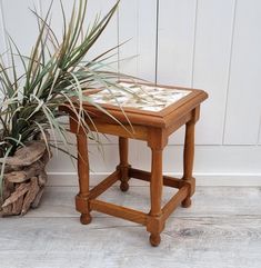 a small wooden table sitting next to a potted plant